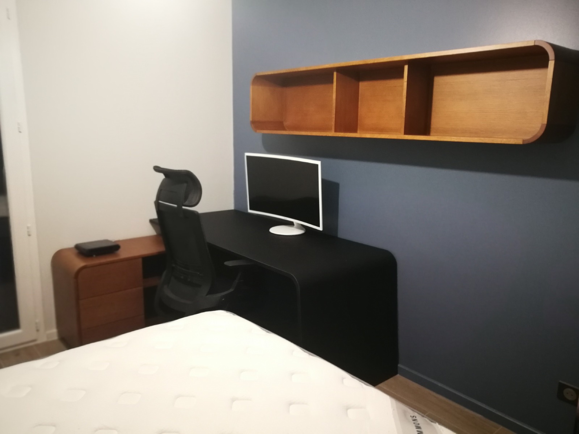 Secretária preta em quarto com prateleira