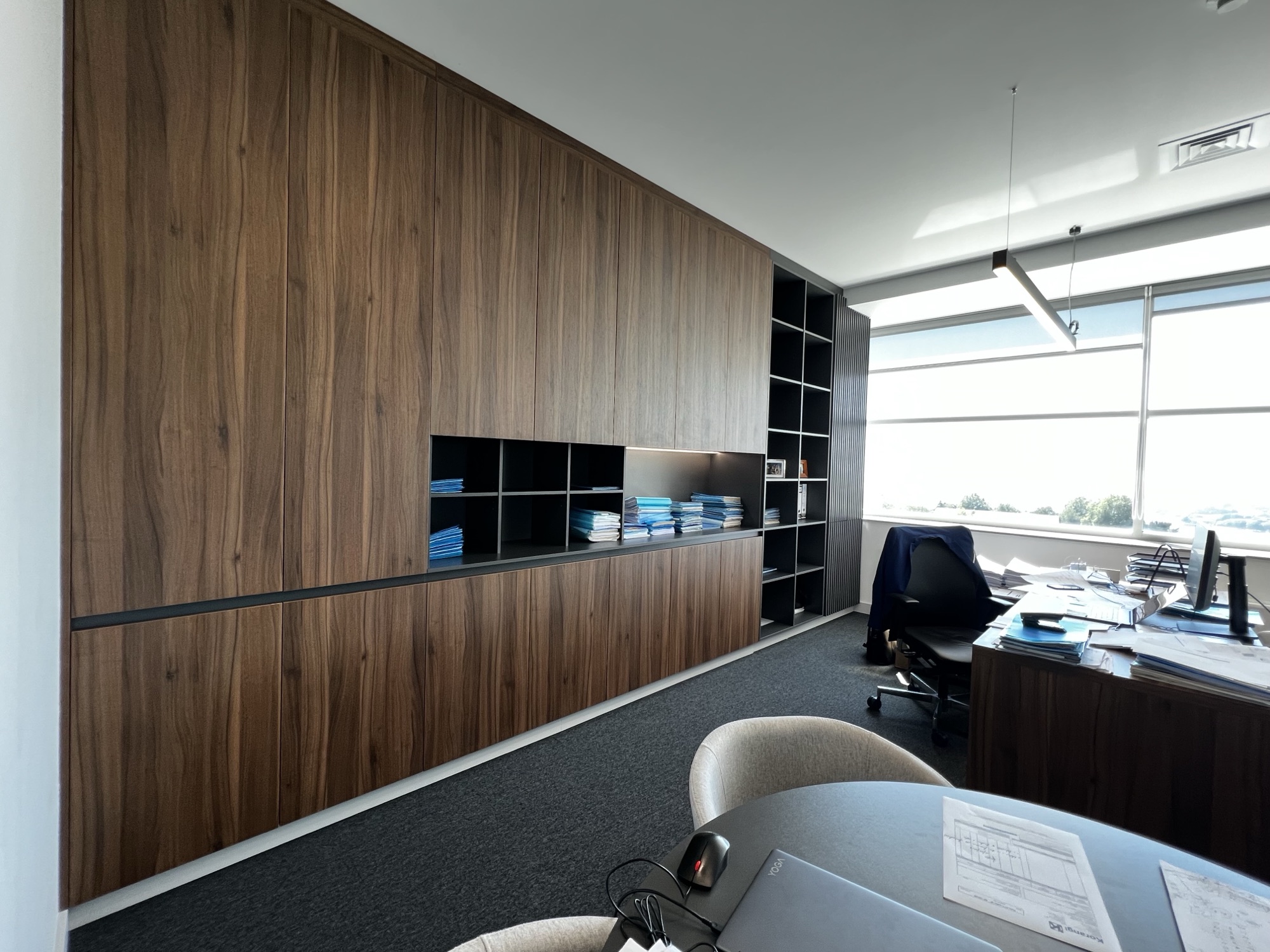 Gabinete com parede em nogueira, estante embutida e secretaria junto a janela panoramica