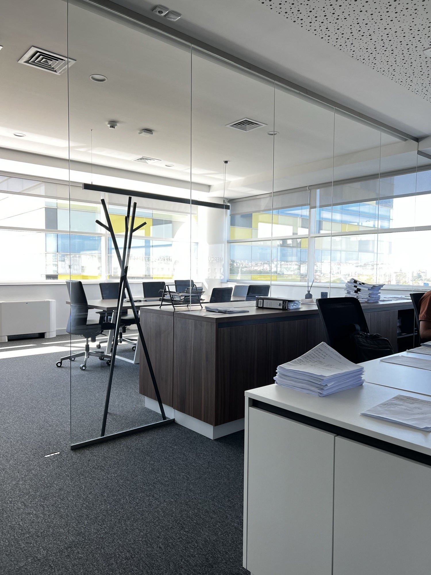 Open space corporativo com divisorias em vidro e postos de trabalho em nogueira