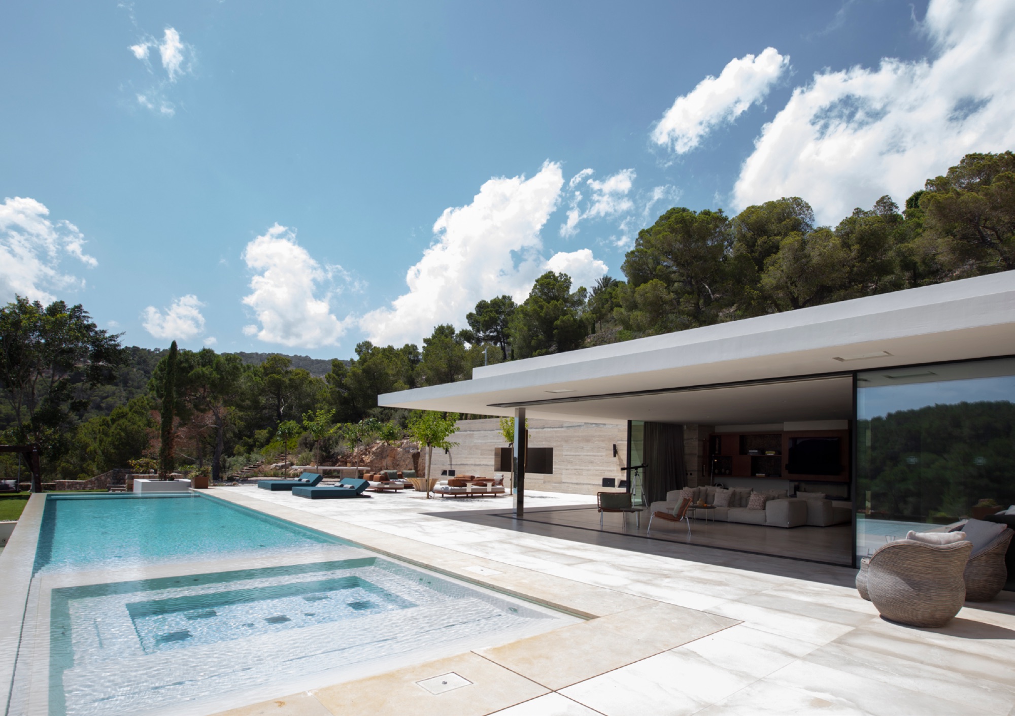 Fachada principal com cobertura plana, piscina infinita com jacuzzi integrado e sala de estar aberta para o exterior