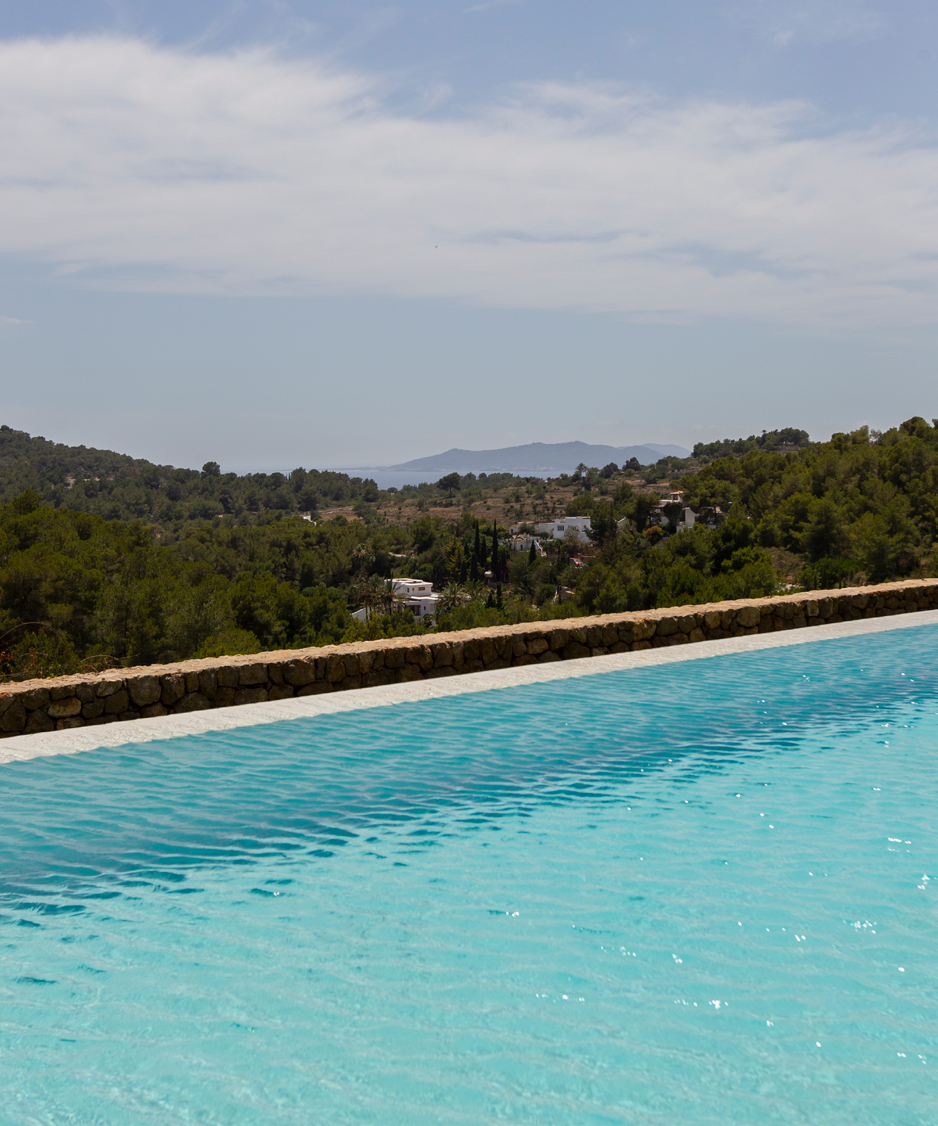 Piscina infinita com vista panoramica sobre as colinas e o mar de Ibiza ao fundo