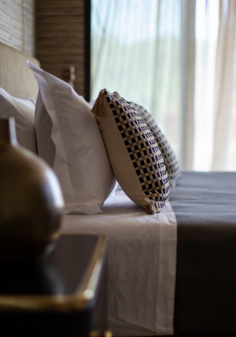 Detalhe de roupa de cama premium com almofadas decorativas e cabeceira estofada em tecido natural