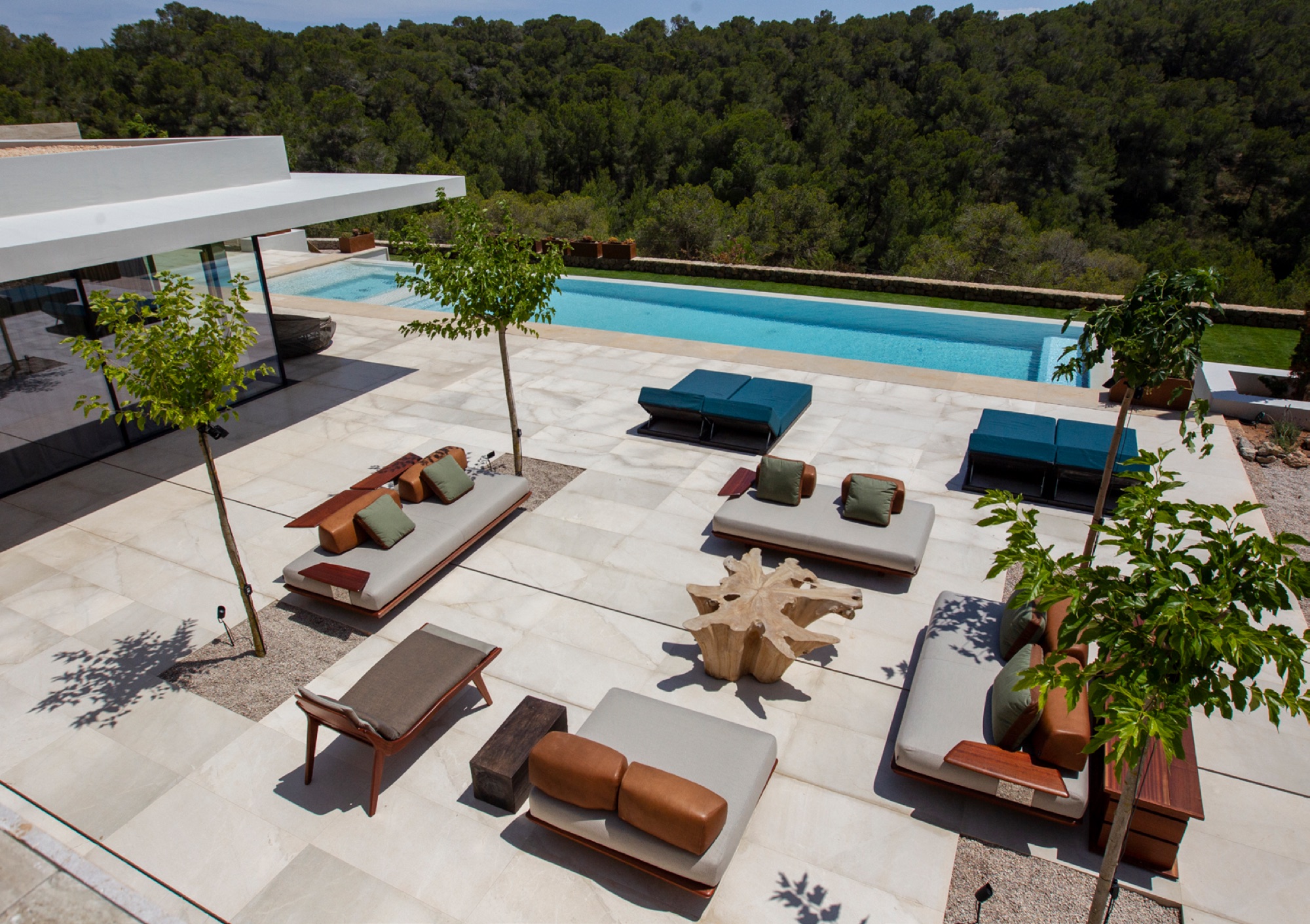 Vista aerea do terraco principal com piscina, daybed em teca, sofas modulares e mesa em raiz de arvore