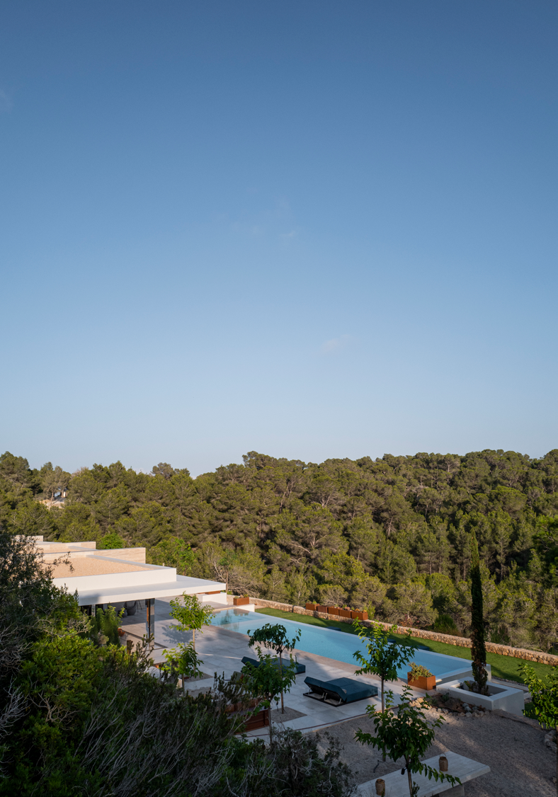Vista panoramica da propriedade ao entardecer com piscina infinita, terracos e floresta de pinheiros