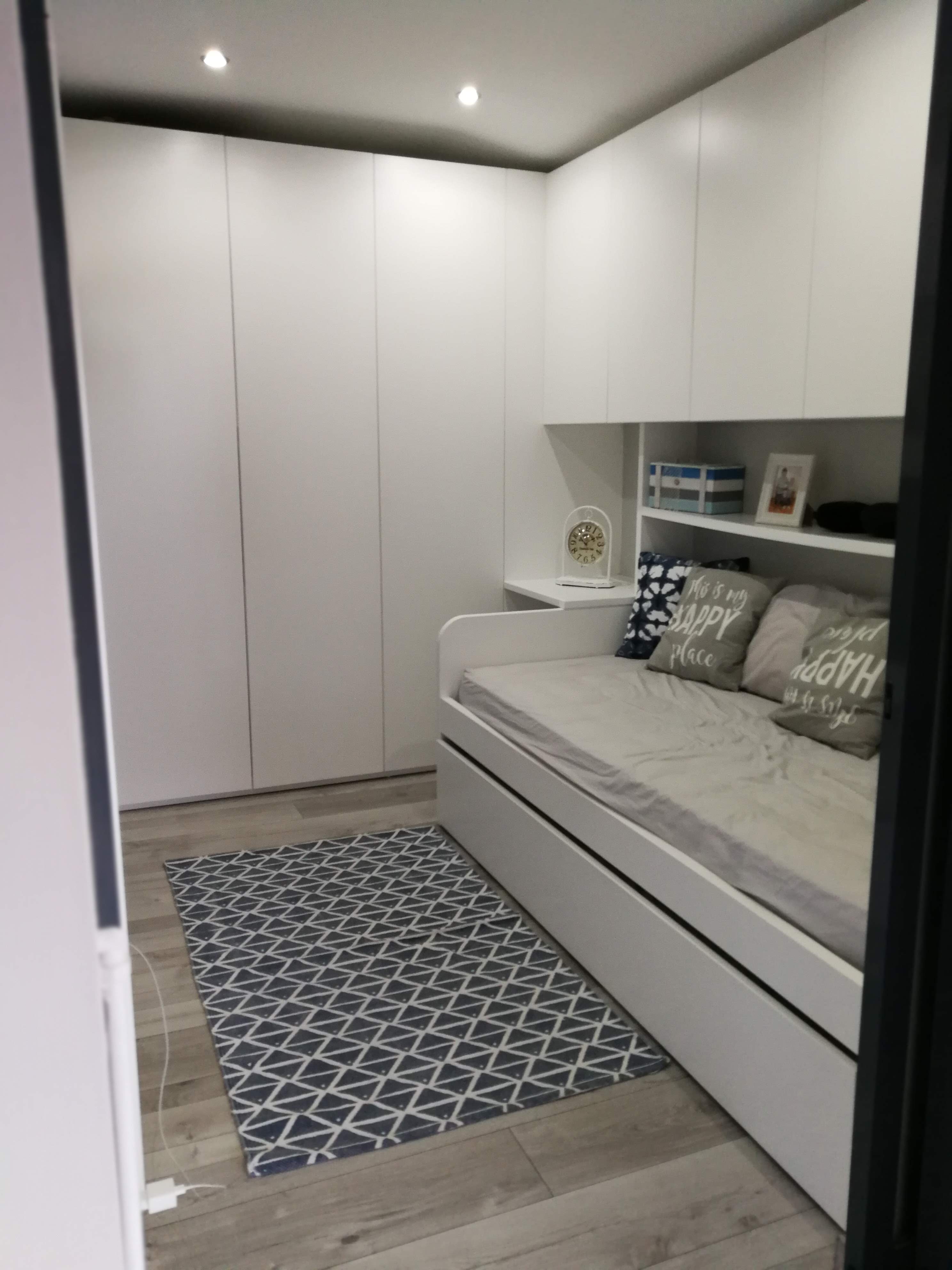 Zona de descanso com armarios ate ao teto, iluminacao embutida e cama com arrumacao