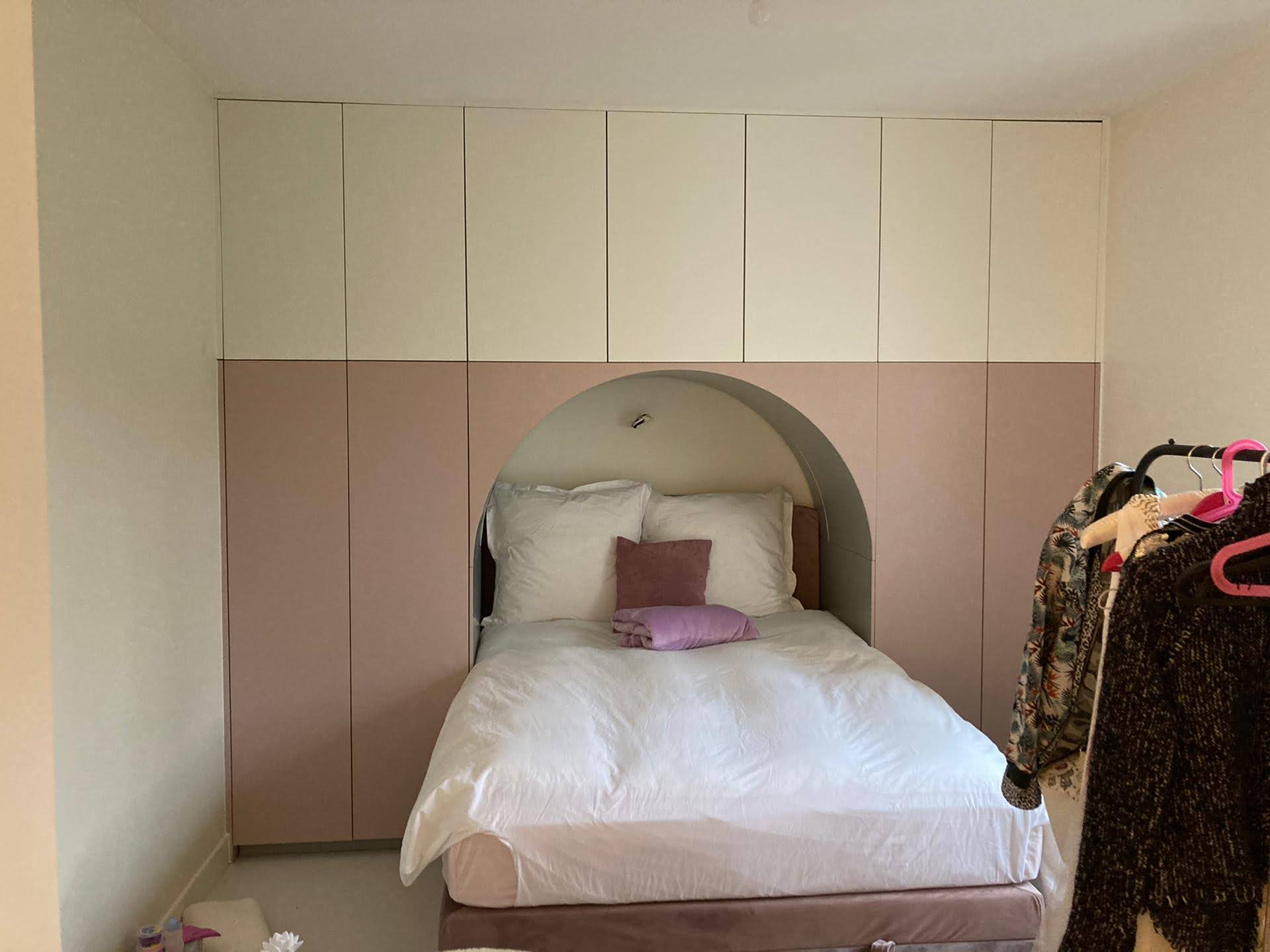 Quarto de crianca com cama embutida em arco e armarios bicolores rosa-velho e branco
